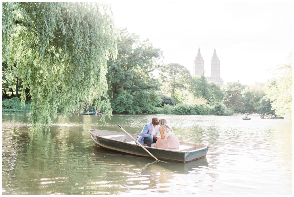 A couple kisses in a row boat on the lake in Central Park, NYC.