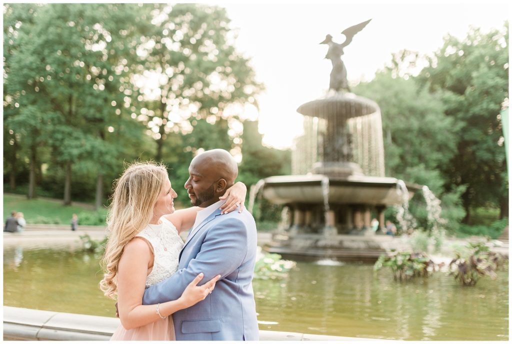 A man and woman embrace in front of the Bethesda Fountain.