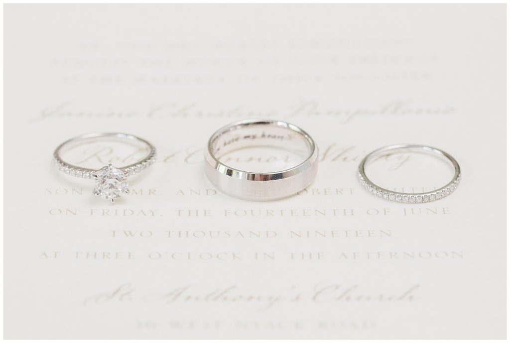 Wedding rings sit on a wedding invitation.