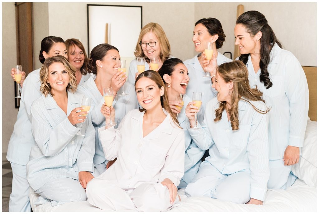 Bride & bridesmaids toast with mimosas while wearing pajamas.