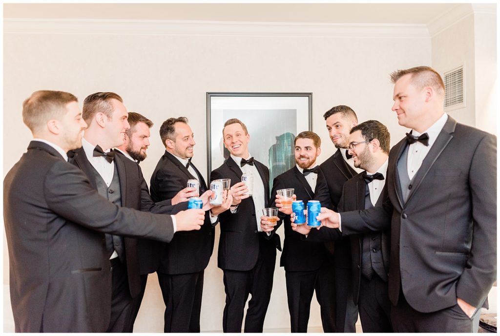 Groom and groomsmen toast with beers.