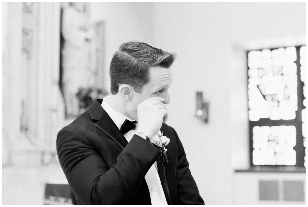 The groom wipes a tear as he watches his bride walk down the aisle.