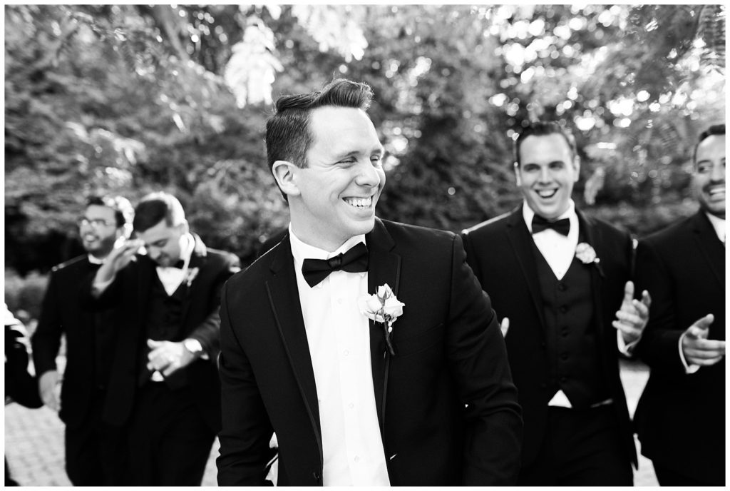 The groom and groomsmen smile and walk through the courtyard.