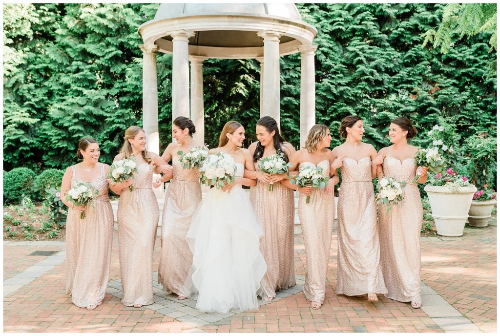 Bride and bridesmaids walk and laugh together.