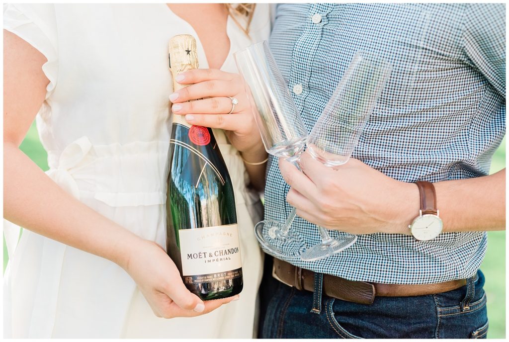 Close up of champagne bottle and glasses in couple's hands.