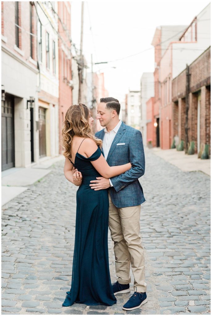 A couple leans in together on a cobblestone street in Hoboken.