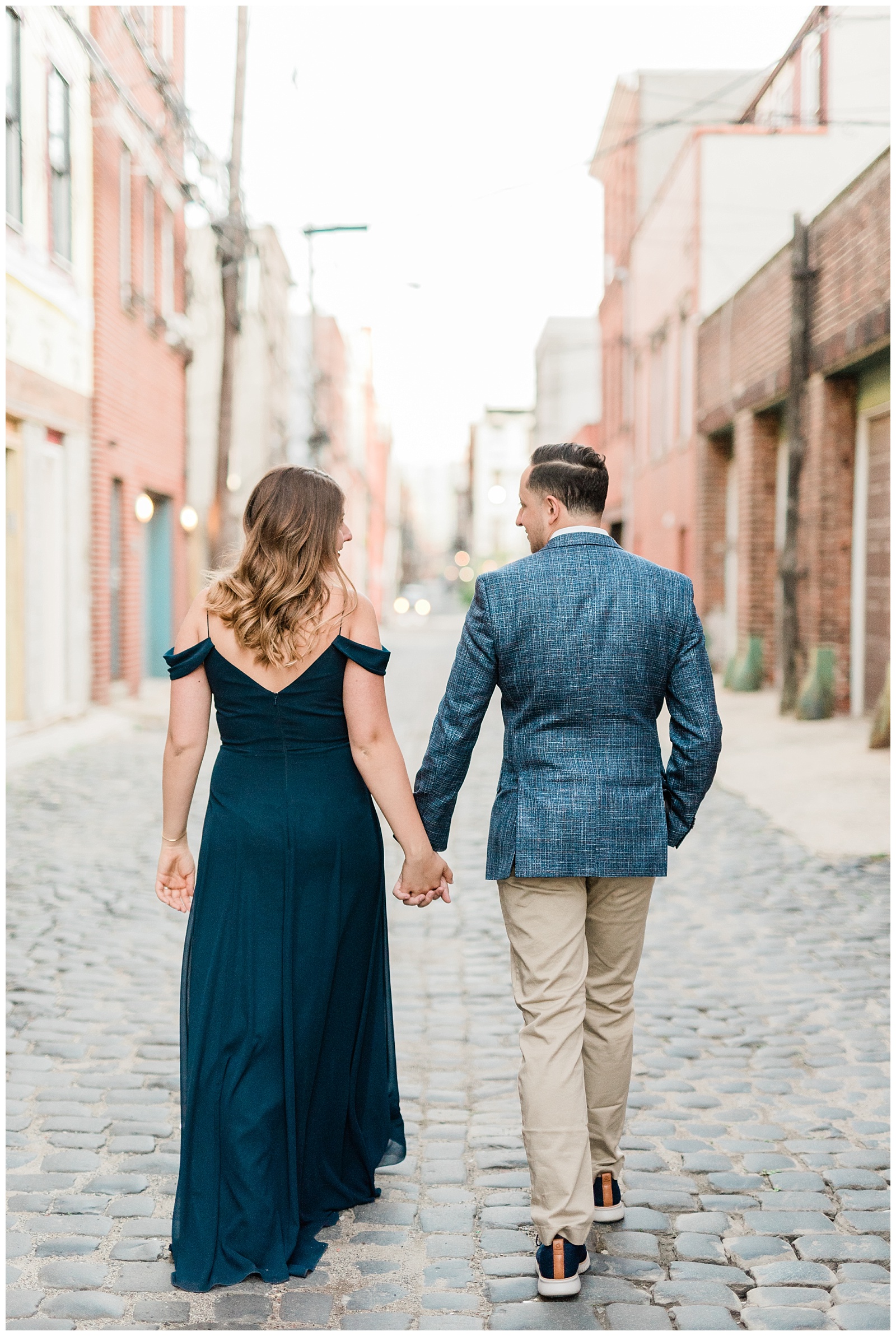 A couple holds hands walking down a cobblestone side street in Hoboken NJ.