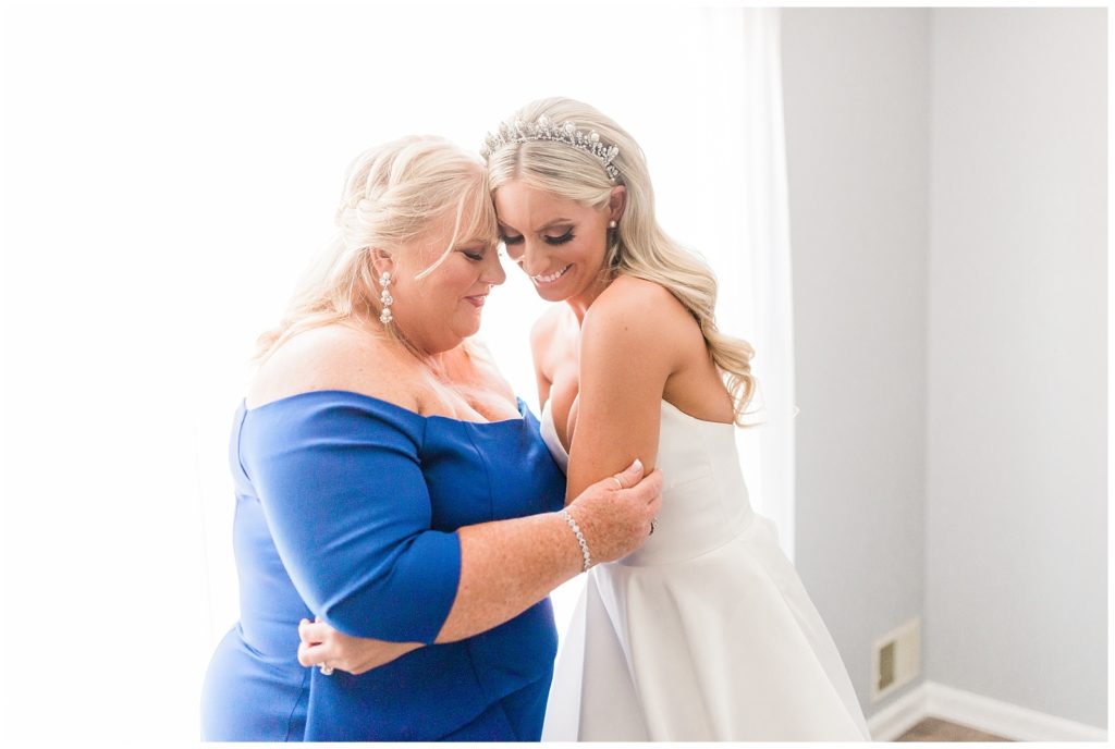 A bride and her mom hug and share a moment after getting into her wedding dress.