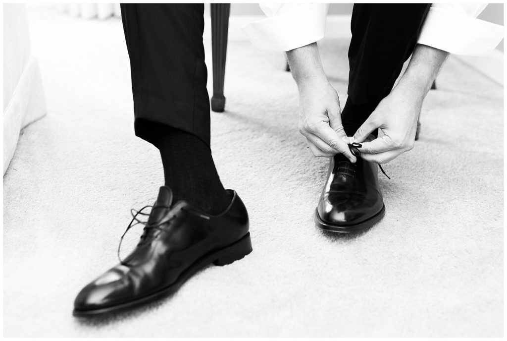 The groom ties his shoes on his wedding day.