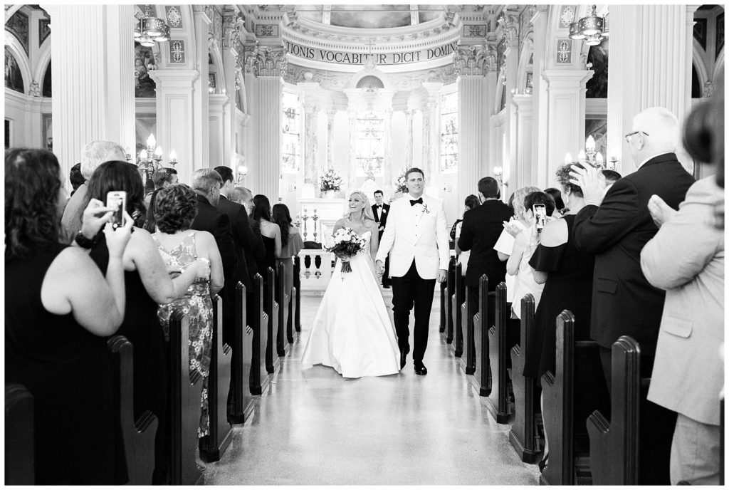 The bride and groom walk down the aisle hand in hand after their wedding ceremony at St. Catharine's Church.