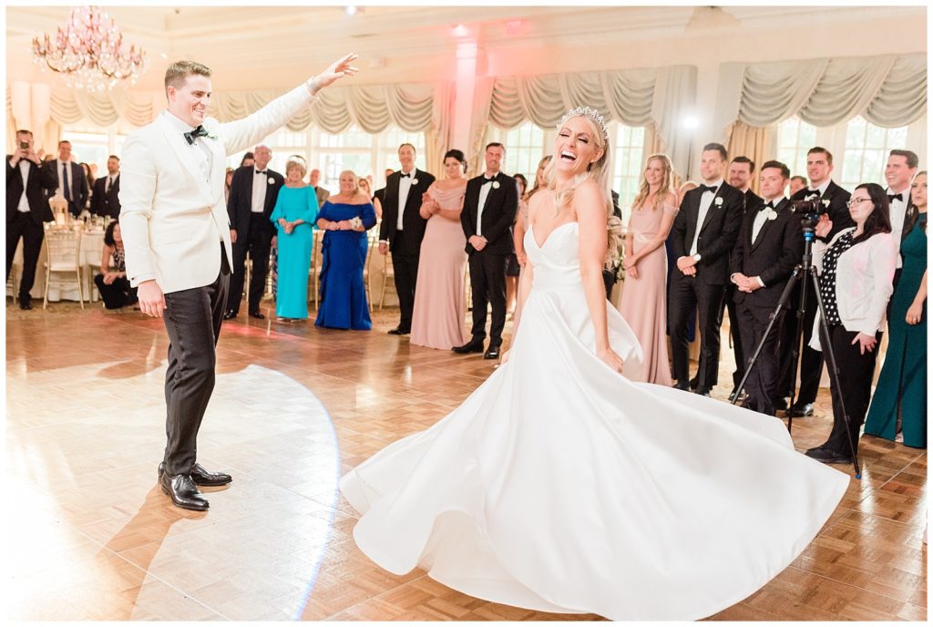 The groom spins the bride as she laughs during their first dance at Eagle Oaks Country Club.