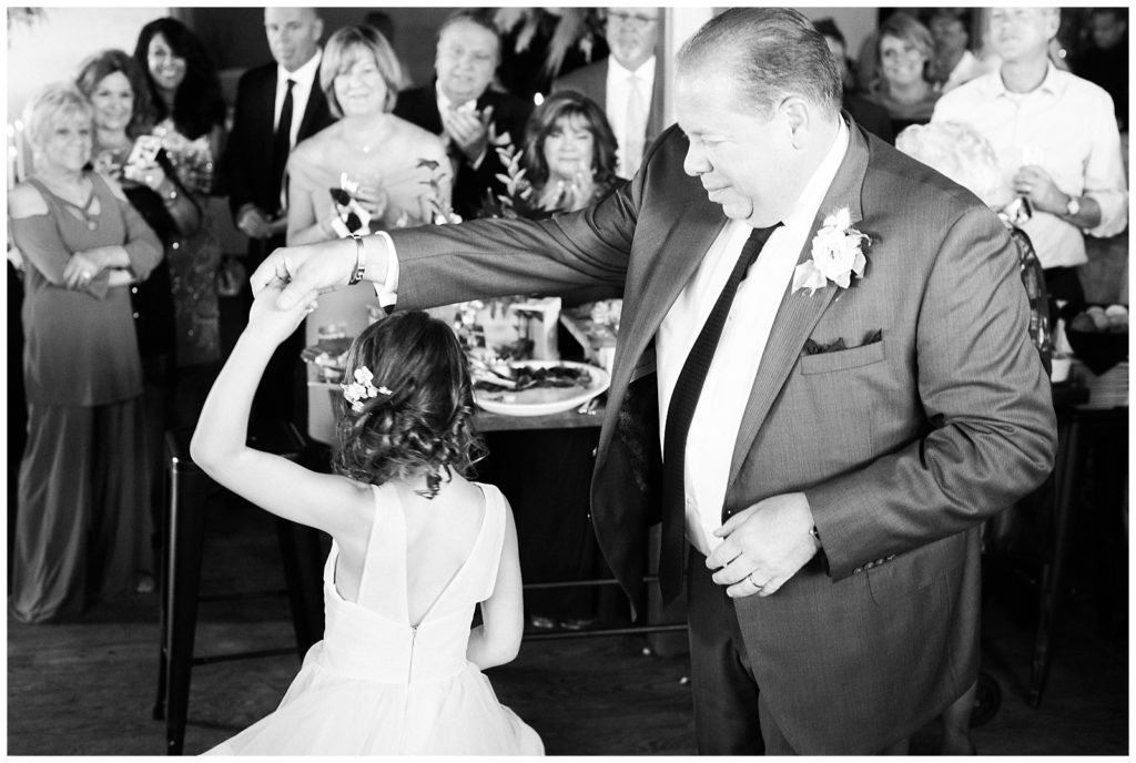 The groom twirls his daughter around the dance floor.