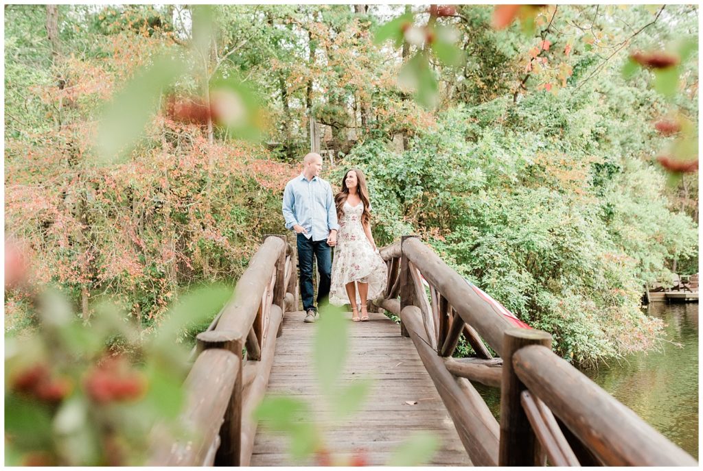 Kellie and Michael walking hand in hand on a wooden bridge through the dense pine barrens. 