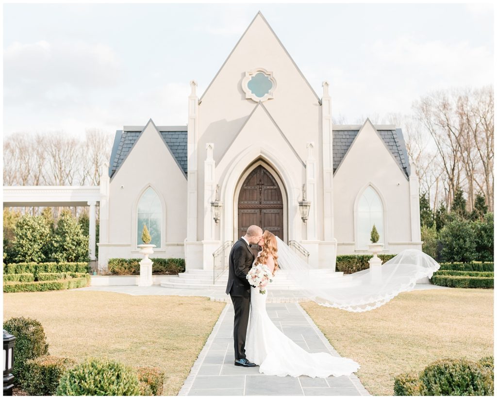 A bride and groom kiss in front of the chapel at Park Chateau wedding venue in East Brunswick, NJ.