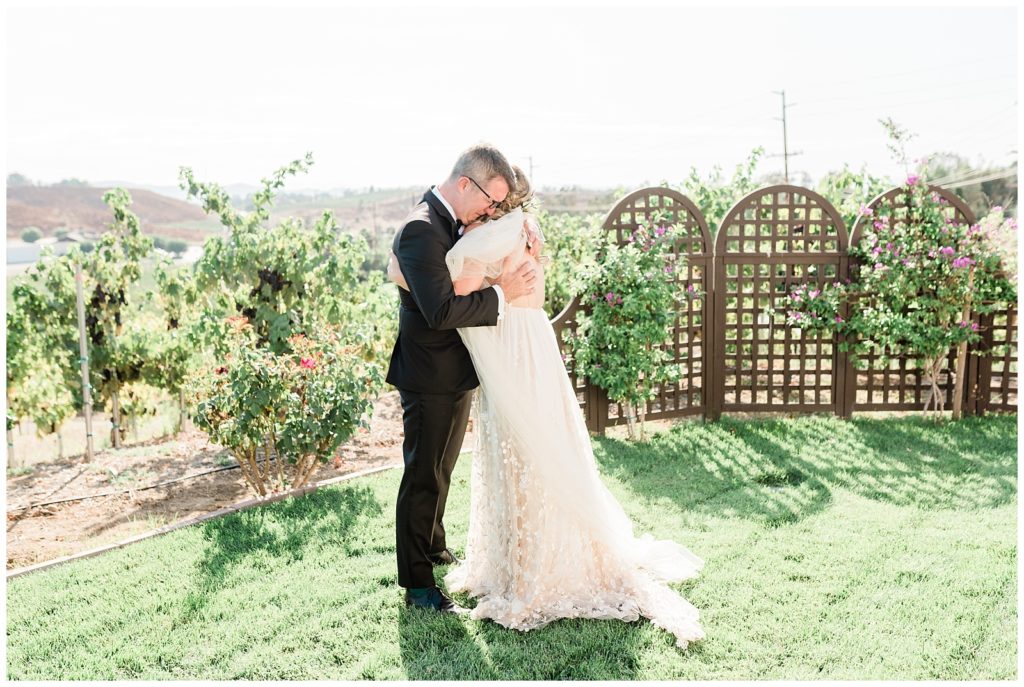 A bride hugs her dad in the gardens outside the bridal cottage at Avensole Winery in Temecula.