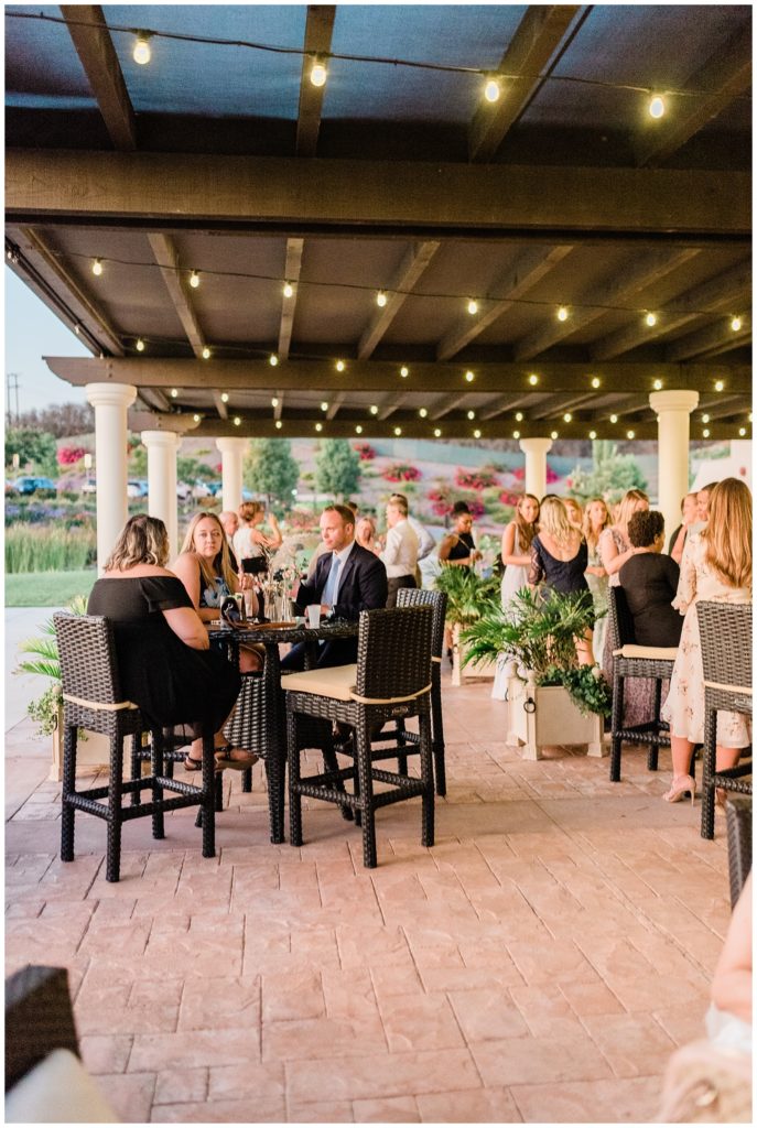 Guests sit outdoors enjoying cocktail hour in the evening at Avensole Winery wedding venue in Temecula, CA.