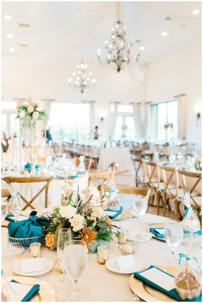 Details on the reception tablescapes including florals and teal napkins and wooden crossback chairs at a wedding reception at Avensole Winery in Temecula, California.