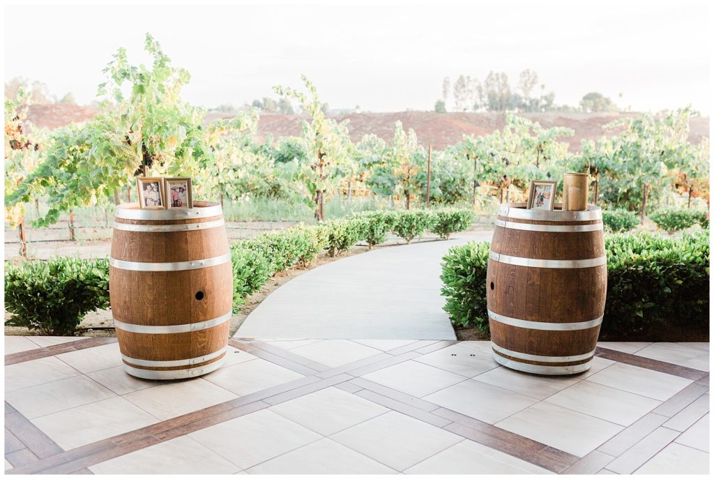 Open air reception space with wine barrels framing a walkway leading through the vineyard at Avensole Winery in Temecula, California.
