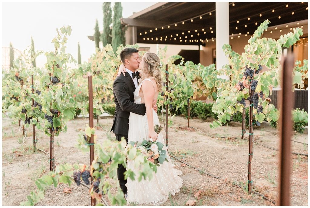 A bride and groom kiss in the vineyards at Avensole Winery wedding venue in Temecula, Southern California.