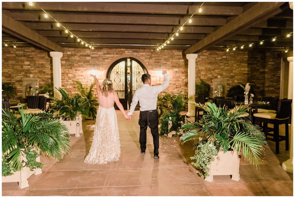 A bride and groom hold hands walking into Avensole Winery wedding venue at night in Temecula, California.
