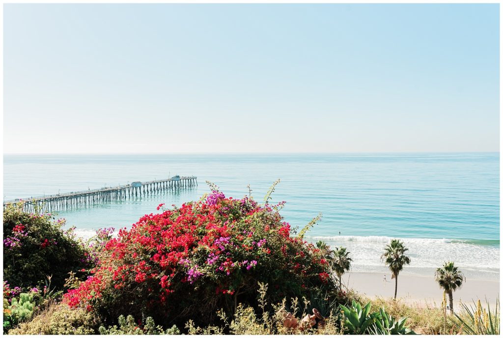 The picturesque view overlooking the San Clemente Pier jutting into the teal pacific ocean on a sunny day at the Casa Romantica wedding venue in Orange County.