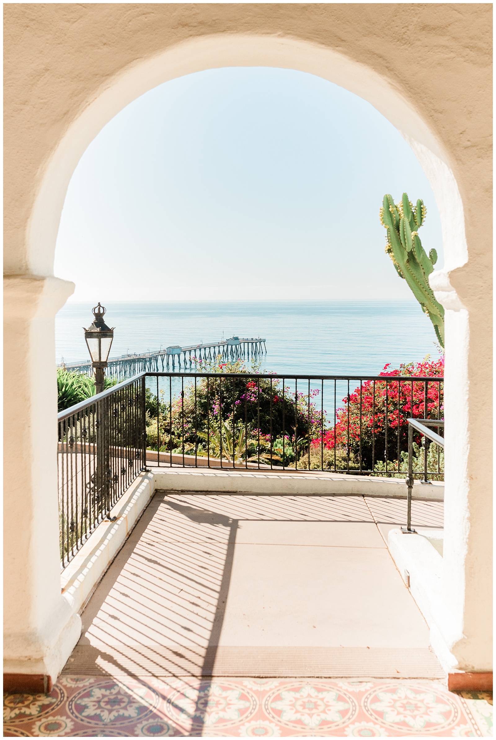 A view of the San Clemente pier and the Pacific Ocean framed in an archway at the Casa Romantica wedding venue in Orange County.
