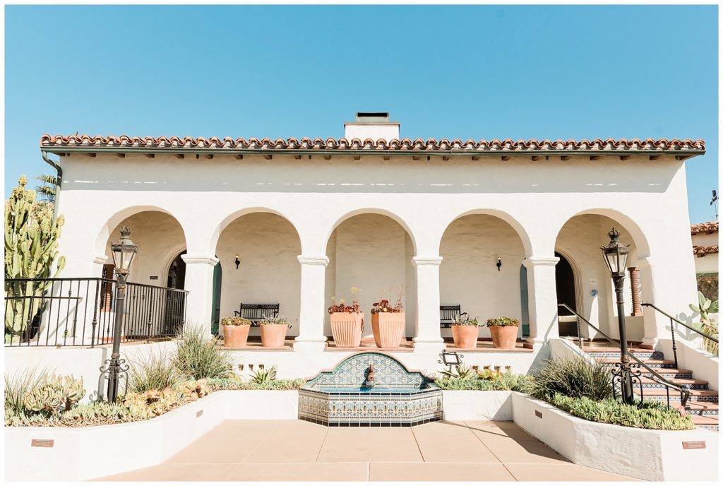 A fountain sits in the middle of an arched covered walkway off the back of the main salon at the Casa Romantica wedding venue.