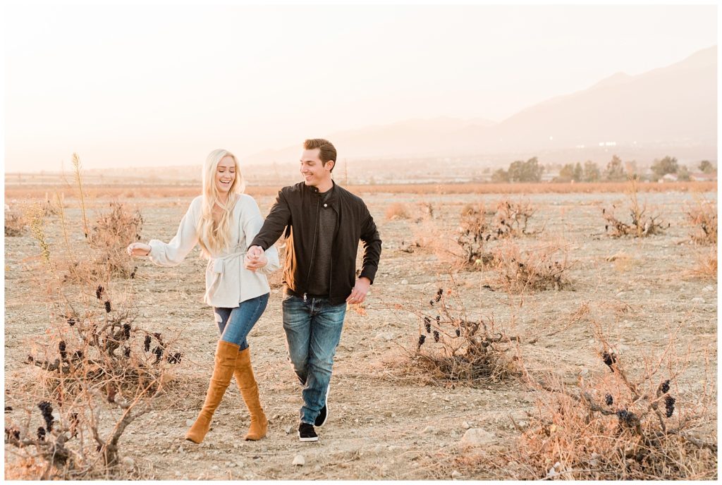 A couple holds hands walking through a desert field in Palm Desert, California for their Anniversary Session.