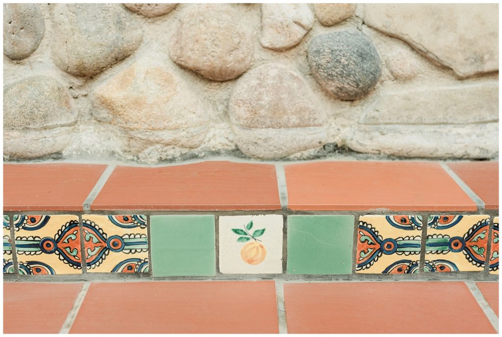 Hand painted tile detail of an orange fruit in the middle, with a colorful paisley design on either side at Rancho Las Lomas, in Orange County.