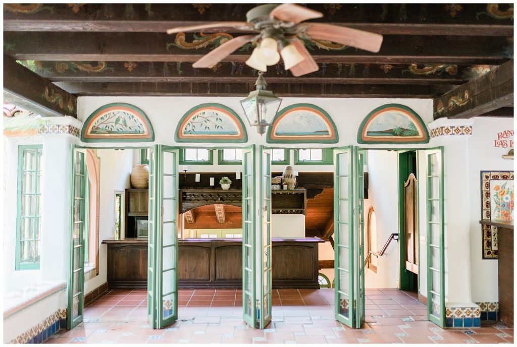 Rancho Las Lomas quadruple green french doors open to welcome in guests at cocktail hour in Rick's Cafe building at the Rancho Las Lomas, Orange County wedding venue in California.