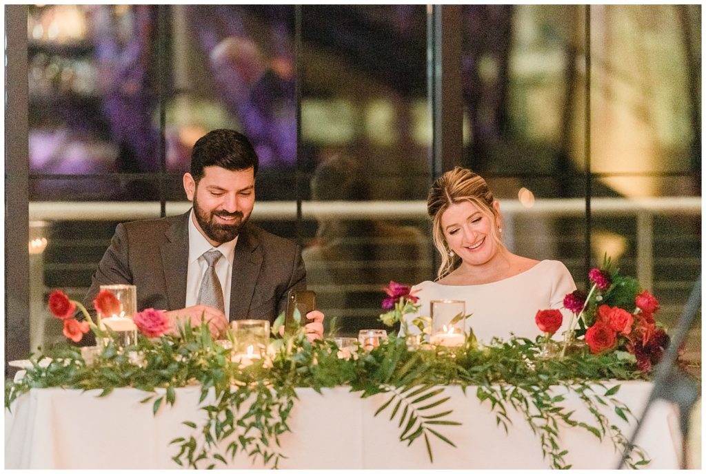 Bride and groom listen to toasts from their sweetheart table at their winter wedding in Beacon NY at Roundhouse Hotel winter wedding inspiration.in Beacon NY at Roundhouse Hotel.