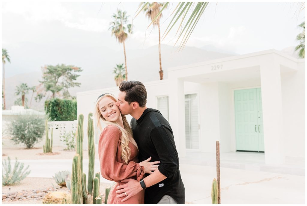 A man kisses his fiancee on the cheek during their Palm Springs California engagement session.