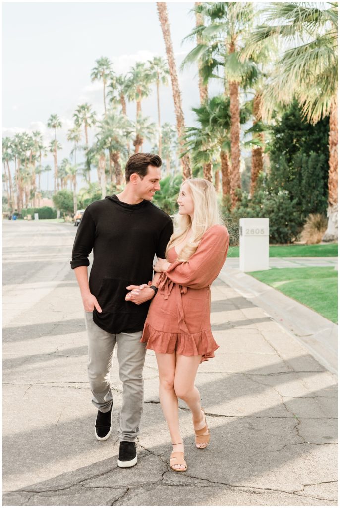 A couple holds hands walking in the street during their Palm Springs engagement session in Southern California.