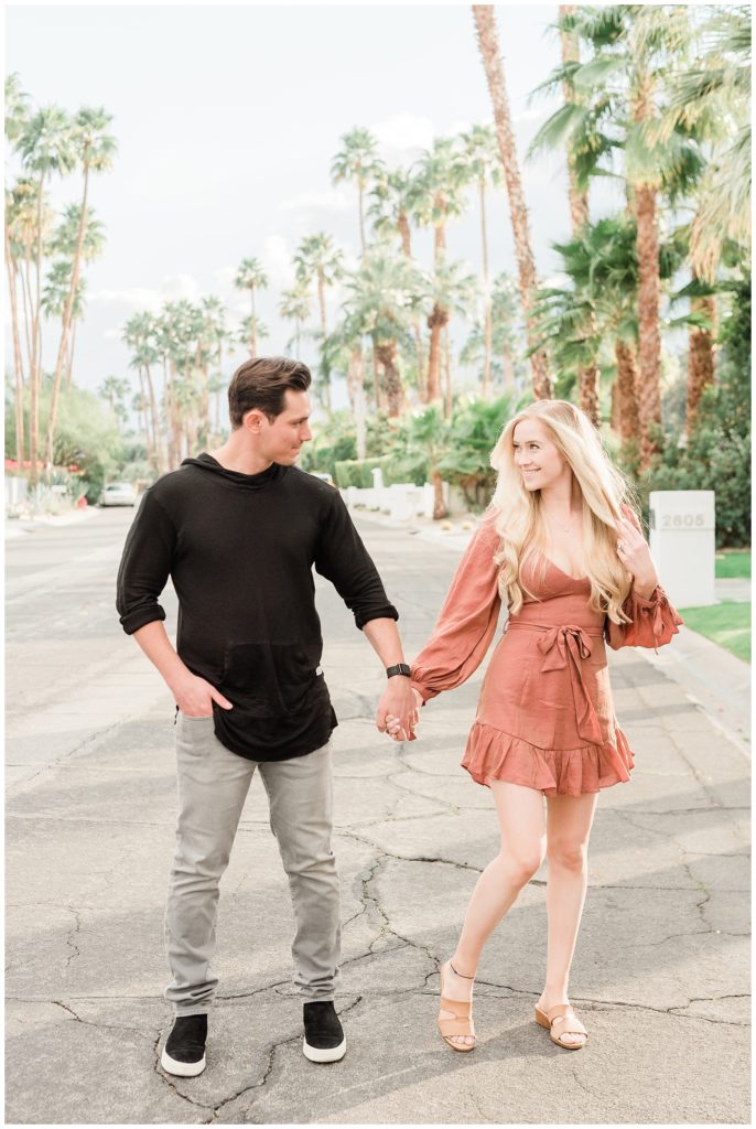 A couple holds hands on a Southern California street in Palm Springs during their engagement session.